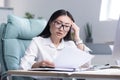 Young Asian woman working on paper in office, businesswoman anxiously examines documents and financial reports Royalty Free Stock Photo