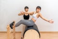 Young Asian woman working on pilates ladder barrel machine with her female trainer during her health exercise