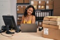 Young asian woman working at small business ecommerce wearing headset looking positive and happy standing and smiling with a Royalty Free Stock Photo