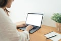 Young Asian woman working using and typing on laptop with mock up blank white screen while at home in office work space. Royalty Free Stock Photo