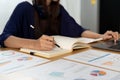 A young asian woman works from home in the kitchen taking notes while using laptop computer for remotely. Royalty Free Stock Photo