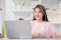 Young asian woman writing on digital tablet while make video conference by laptop computer Royalty Free Stock Photo