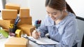 Young Asian woman is writing down the customer`s details and addresses on the mailbox in order to prepare for shipping Royalty Free Stock Photo