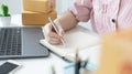 Young Asian woman is writing down the customer`s details and addresses on the Clipboard in order to prepare. Royalty Free Stock Photo