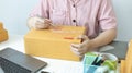 Young Asian woman is writing down the customer`s details and addresses on the Clipboard in order to prepare. Royalty Free Stock Photo