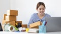 Young Asian woman is writing down the customer`s details and addresses on the mailbox in order to prepare for shipping Royalty Free Stock Photo