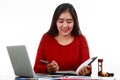 Young Asian woman writing the memo while checking sale volume graph with smiling Royalty Free Stock Photo