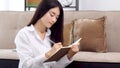 Young asian woman writing on notebook paper at home office