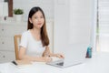 Young asian woman writing on notebook for planning working and using laptop computer on desk at home. Royalty Free Stock Photo