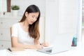 Young asian woman writing on notebook for planning working and using laptop computer on desk at home. Royalty Free Stock Photo