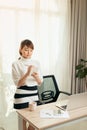 Young Asian woman writing notebook while standing behind working desk at home Royalty Free Stock Photo