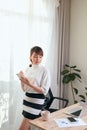 Young Asian woman writing notebook while standing behind working desk at home Royalty Free Stock Photo