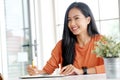 Young asian woman wrting on notebook paper on table at home office