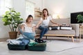 Young Asian woman packing clothes to the suitcase sitting on the sofa. Preparation for the summertime vacation. Two Royalty Free Stock Photo