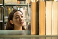 Young Asian women are searching for books and reading from the bookshelves in the college library to research and develop Royalty Free Stock Photo