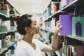 Young Asian women are searching for books and reading from the bookshelves in the college library to research and develop Royalty Free Stock Photo