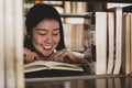 Young Asian women are searching for books and reading from the bookshelves in the college library to research and develop Royalty Free Stock Photo