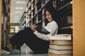 Young Asian women are searching for books and reading from the bookshelves in the college library to research and develop Royalty Free Stock Photo