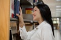 Young Asian women are searching for books and reading from the bookshelves in the college library to research and develop Royalty Free Stock Photo
