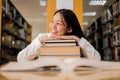 Young Asian women are searching for books and reading from the bookshelves in the college library to research and develop Royalty Free Stock Photo