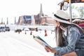 Young Asian women sitting in local taxi holing a map with Grand Palace as a blurred background, Bangkok Thailand