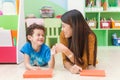 Young asian woman teacher teaching american kid in kindergarten classroom with happiness and relaxation. Royalty Free Stock Photo