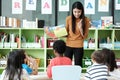Young asian woman teacher teaching kids in kindergarten classroo