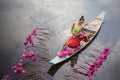 Young Asian women in Traditional dress in the boat and pink lotus flowers in the pond.