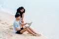 Young Asians sit on a laptop video chatting on a laptop, in a chair by the sea, comfortably,