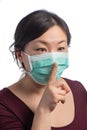 Young asiatic woman wearing a protection mask making a silence hand sign on a white background