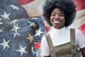 Young aspiring black girl looking in the future with a smile. A US flag on the background.