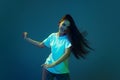 Young astonished girl with long loose hair dancing isolated on blue background in neon light. Concept of beauty, art