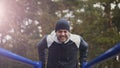 Young athlete man doing push-ups exercise on bars in winter park outdoors Royalty Free Stock Photo