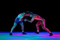 Young athlete man, wrestlers in blue and red uniform hand wrestling in neutral position on their feet in neon lights