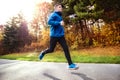 Young athlete running in park in colorful autumn nature. Royalty Free Stock Photo