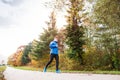 Young athlete running in park in colorful autumn nature. Royalty Free Stock Photo