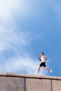 Young athlete runs against the blue sky. Sports creative image.