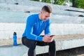 A young athlete sits in the stands and listens to music after training