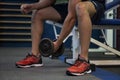 Young athlete sitting on a bench and lifting weights in a gym Royalty Free Stock Photo