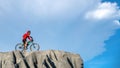 Young athlete standing on a rock with bicycle. Cyclist riding mountain bike on the rocky trail at sunset. Extreme mountain bike sp