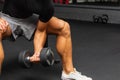 Young athlete Working out biceps at the gym.Closeup muscular young man lifting weights in gym on a dark background