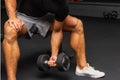 Young athlete Working out biceps at the gym.Closeup muscular young man lifting weights in gym on a dark background