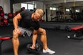 Young athlete Working out biceps at the gym.Closeup muscular young man lifting weights in gym on a dark background