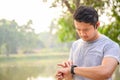 Young athletes take a break during exercise in the park and adjust their smart watches. Asian men set up their smartwatch before Royalty Free Stock Photo