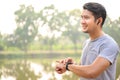 Young athletes take a break during exercise in the park and adjust their smart watches. Asian men set up their smartwatch before Royalty Free Stock Photo