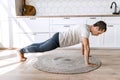 Young athletic attractive man practicing yoga lesson at home on the floor, doing push-ups exercises, standing in plank Royalty Free Stock Photo