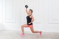 Young athletic beautiful blonde woman wearing pink shorts and black top holding dumbbell.