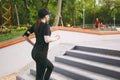 Young athletic beautiful brunette girl in black uniform, cap with headphones doing sport exercises, training and running Royalty Free Stock Photo