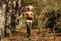 A young athletic blond hair woman runs jumping in a good mood in the park. Royalty Free Stock Photo