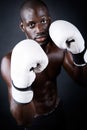 Young athletic boxer wearing gloves in black background.